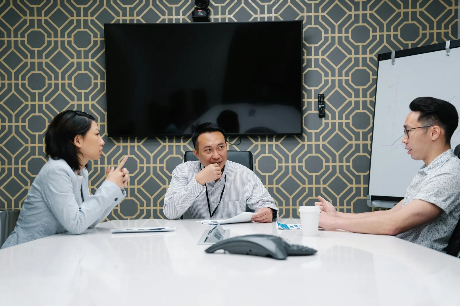 Three colleagues in conversation around a meeting table