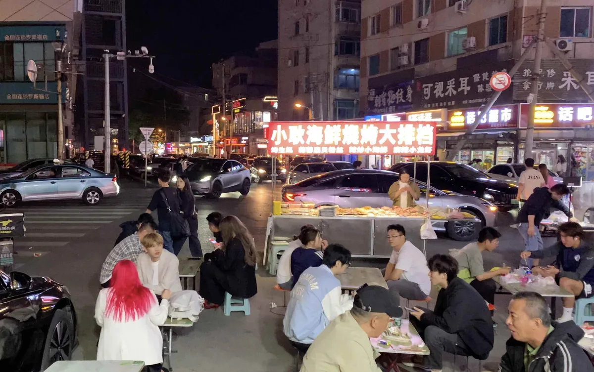 Wide view of Dalian outdoor BBQ street with glowing red sign