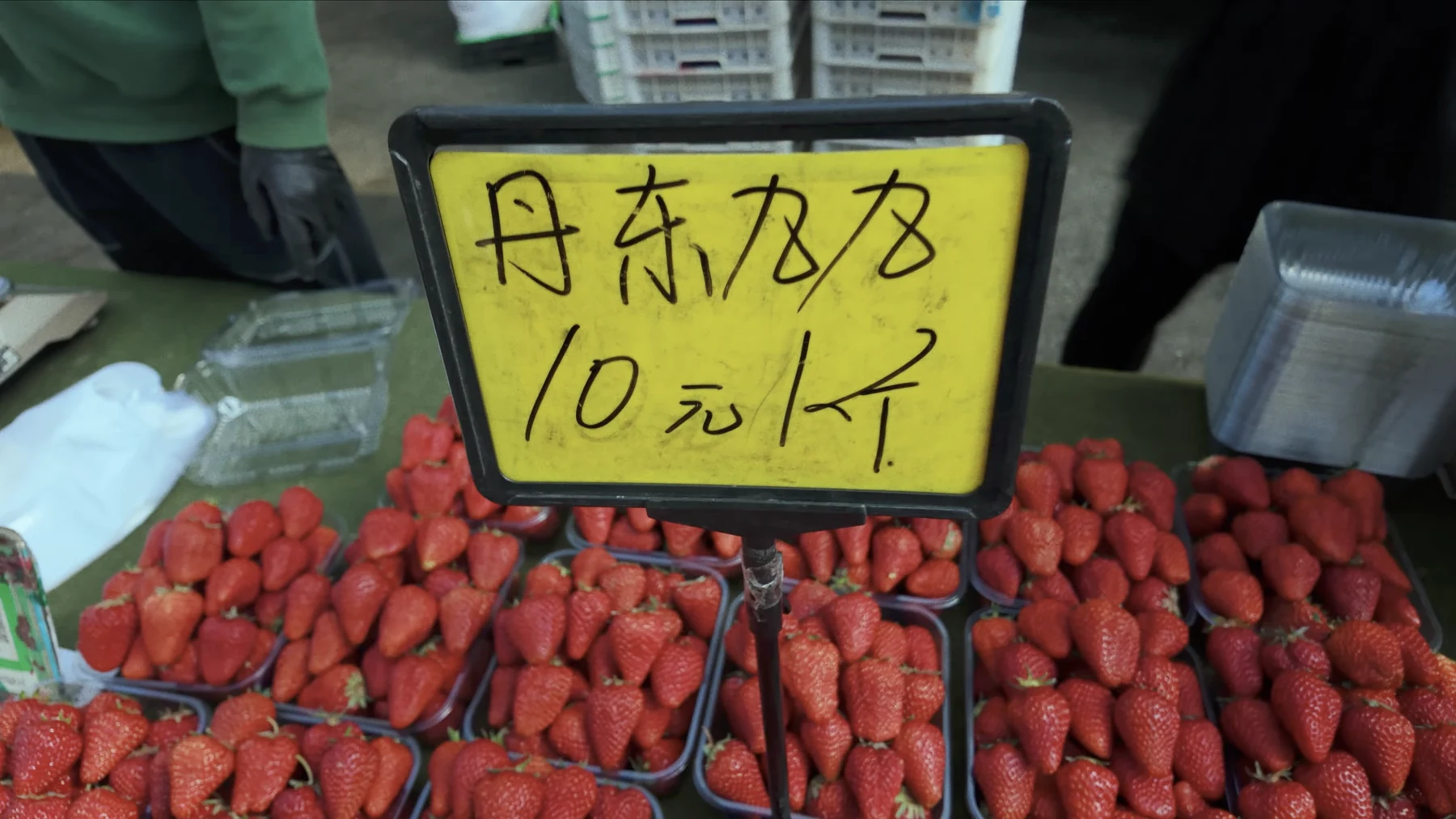 Handwritten yellow market sign reading Dandong 99 strawberries 10 yuan per jin