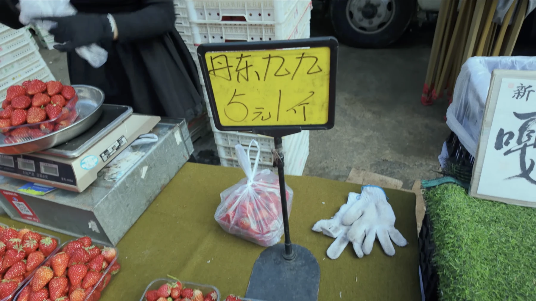 Handwritten yellow market sign reading Dandong 99 strawberries 5 yuan per jin
