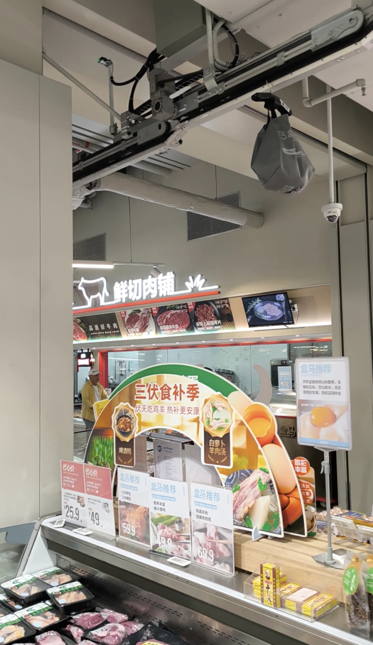 Insulated gray order bag hanging from an overhead conveyor rail in a Shanghai Freshippo supermarket