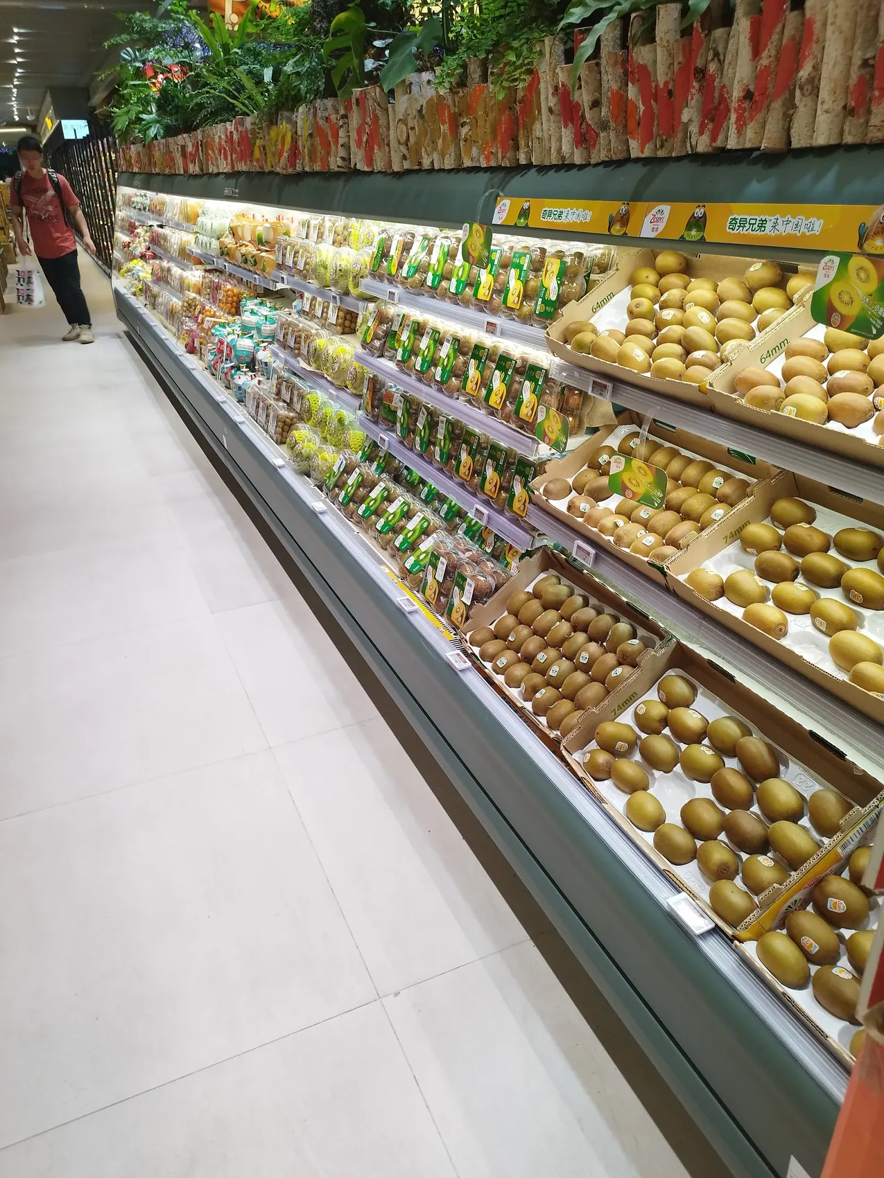 Brightly lit supermarket fruit hall in Shanghai with neatly stacked mangoes, oranges and melons
